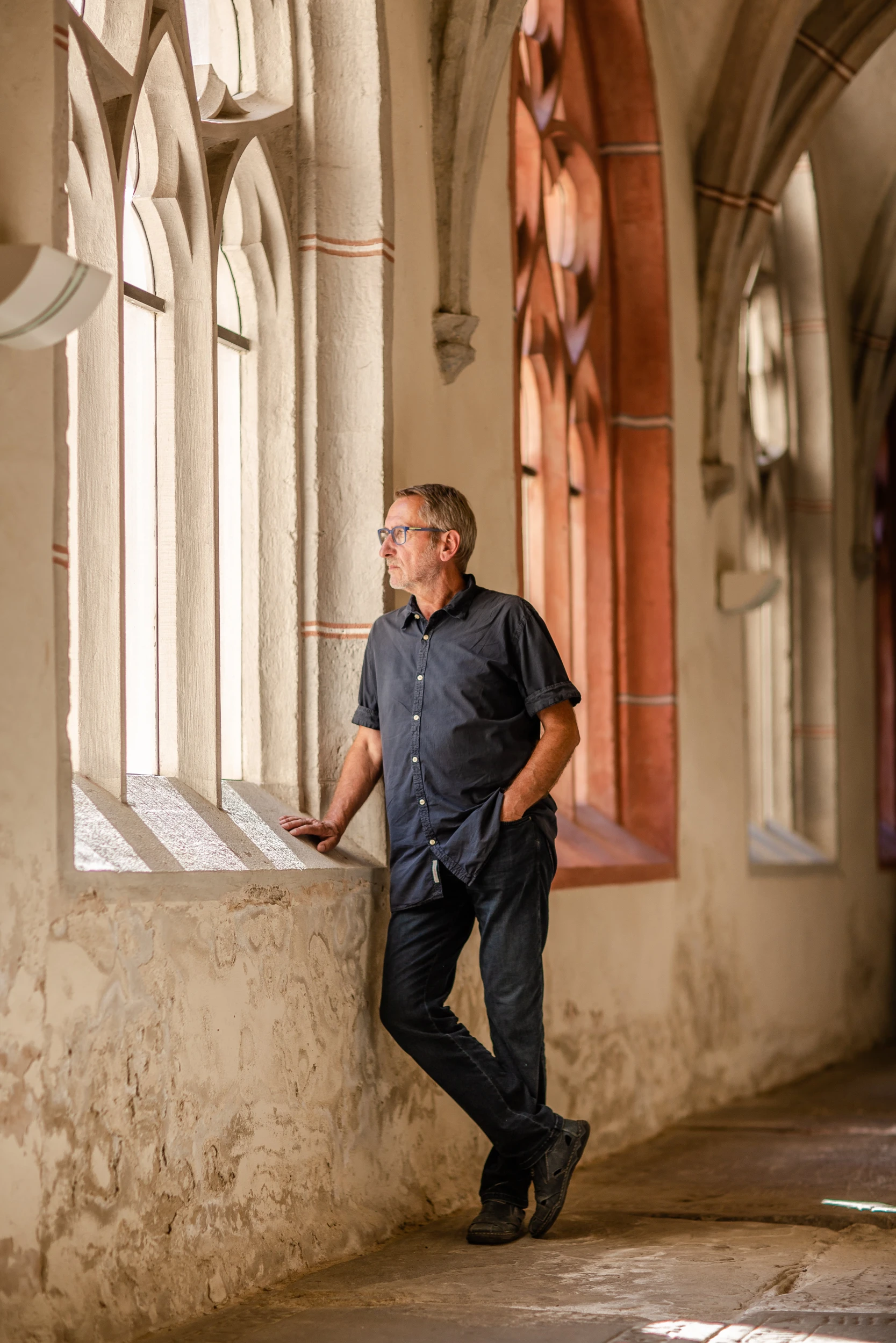 Reiner Eckel lehnt an einem gotischen Fenster im Kreuzgang des Zeitzer Doms.